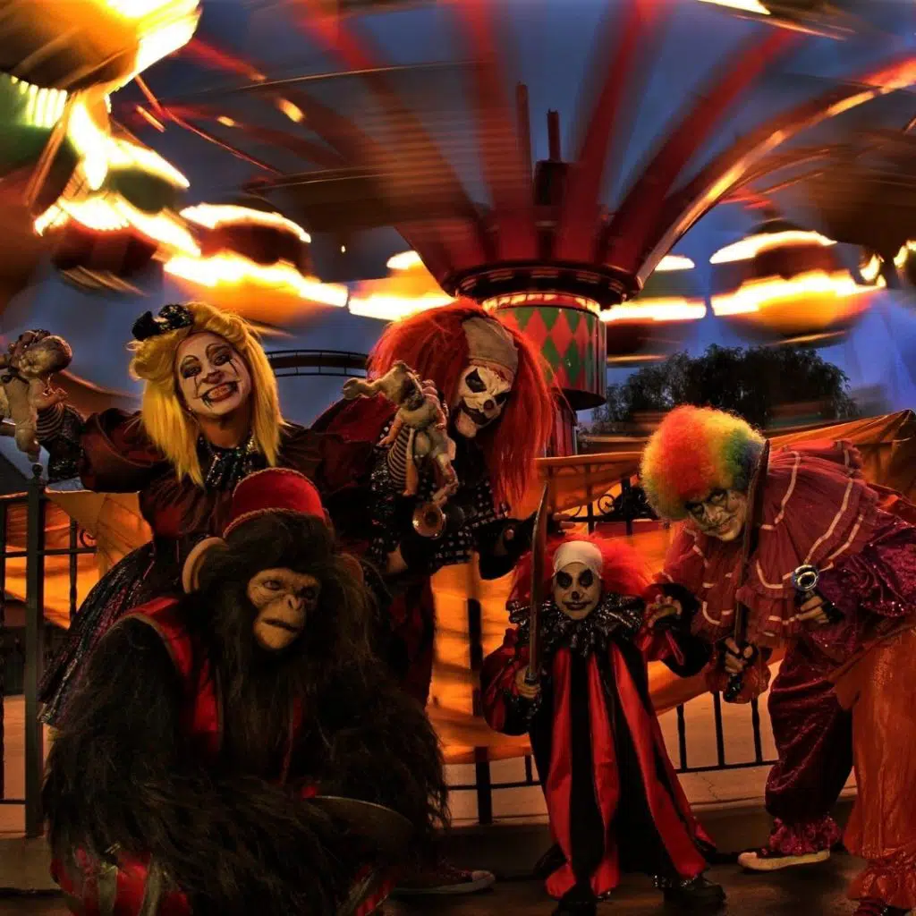 Photo of creepy clowns posing near an amusement park ride.