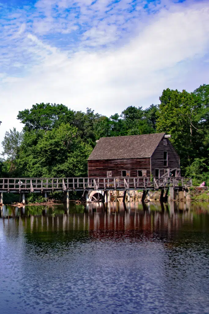 Photo of a wooden house with a water wheel and bridge.