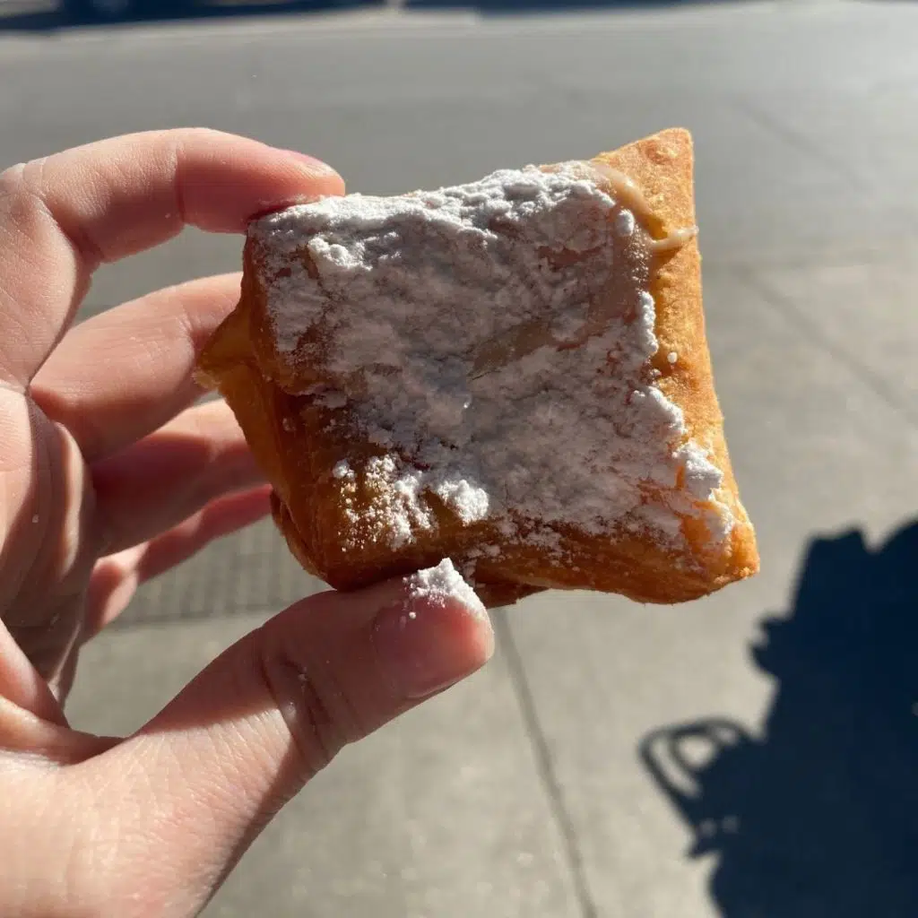 Closeup of a beignet with powdered sugar.