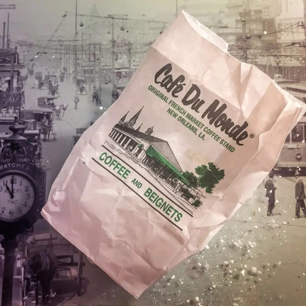 Flat lay photo of a bag of beignets from Café Du Monde with powdered sugar all over the table.
