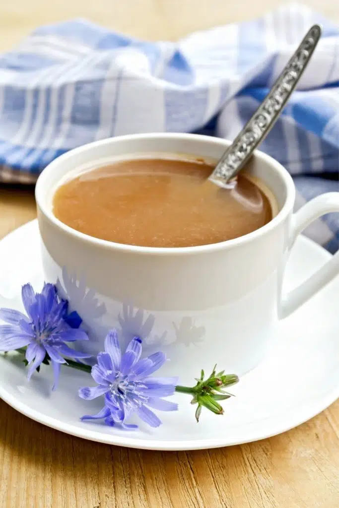 Closeup of a cafe au lait with chicory root flower next to the cup.