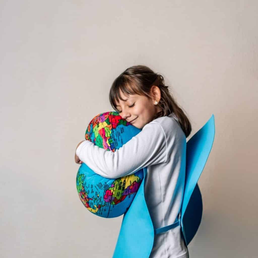 Photo of a young girl hugging a squishy world globe.