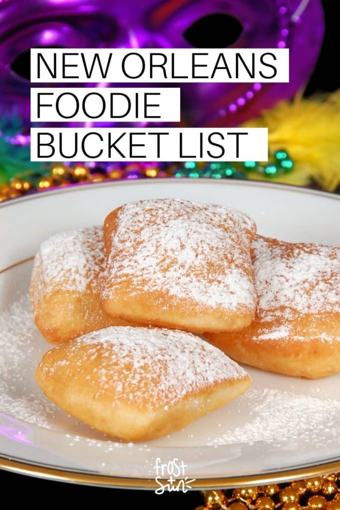 Closeup of a plate of beignets with powdered sugar. Text above the photo reads "New Orleans Foodie Bucket List."