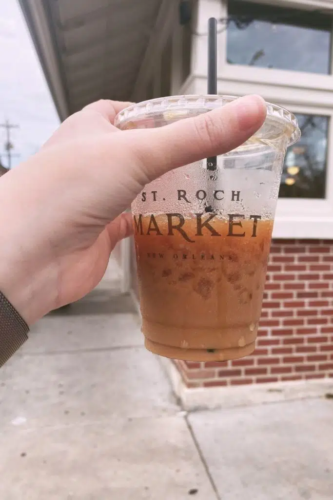 Photo of a person holding a cup of iced coffee from St. Roch Market in New Orleans.