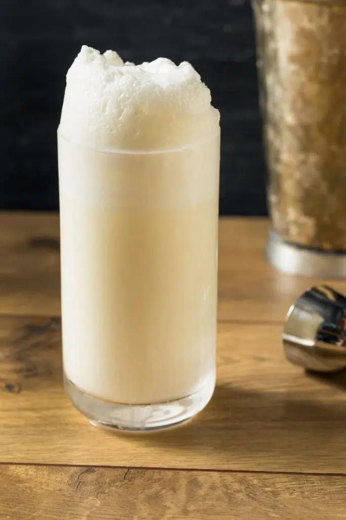 Closeup of a ramos gin fizz cocktail with a frothy foam on top.