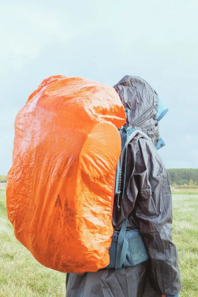 Photo of a person with a large backpack with a rain cover on top.