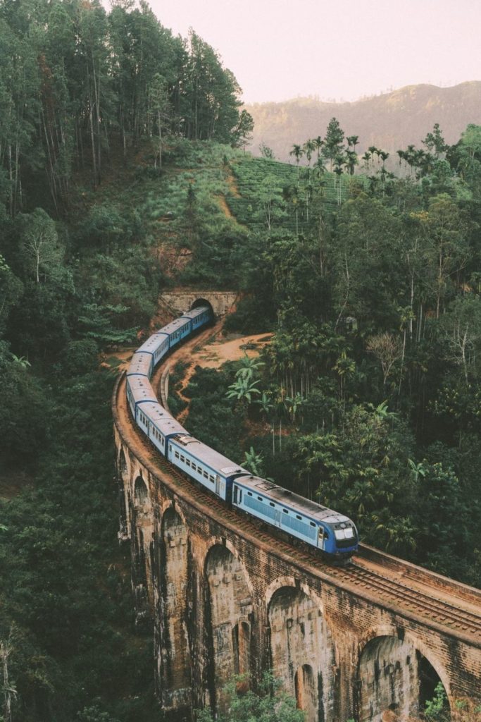 Photo of a blue train crossing the Nine Arches Bridge in Sri Lanka.