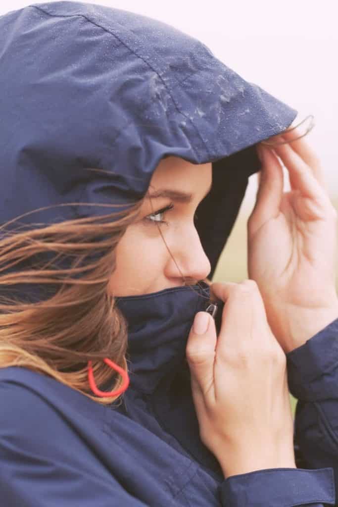 Photo of a woman wearing a navy packable rain jacket.