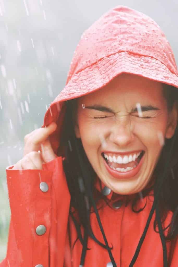 Closeup of a woman wearing a red waterproof hat in the rain.