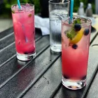 Closeup of 2 blueberry mojitos and a glass of water.