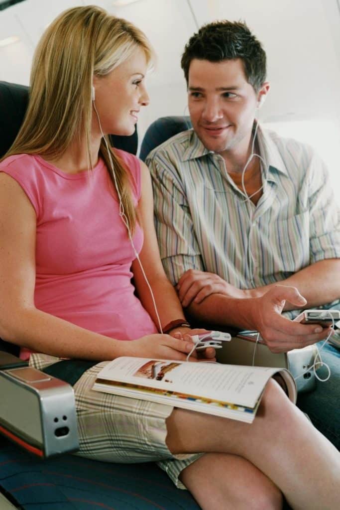 Photo of a young man and woman chatting on a plane.