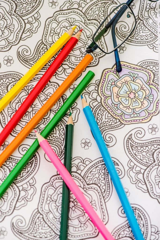 Closeup of an adult coloring sheet and several coloring pencils.