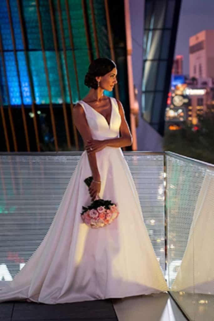 Photo of a bride holding a bouquet while looking out over the Las Vegas Strip from the Waldorf Astoria hotel.