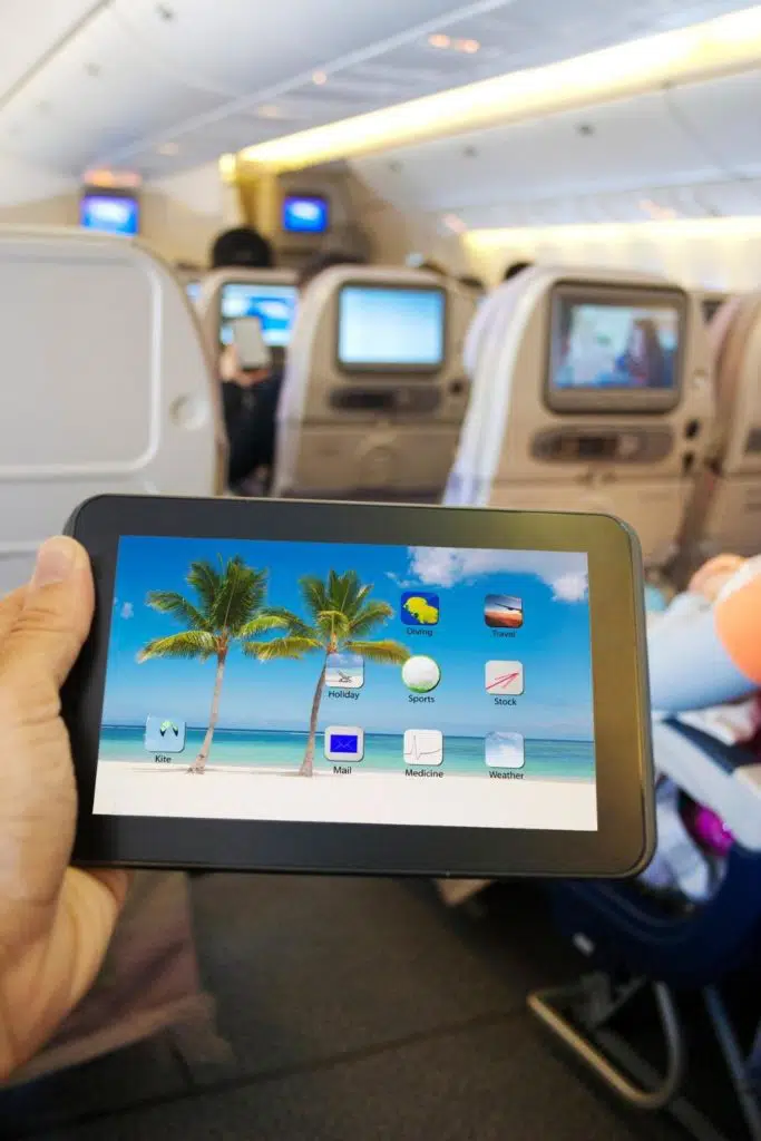 Photo of a person holding up a tablet while on a plane.