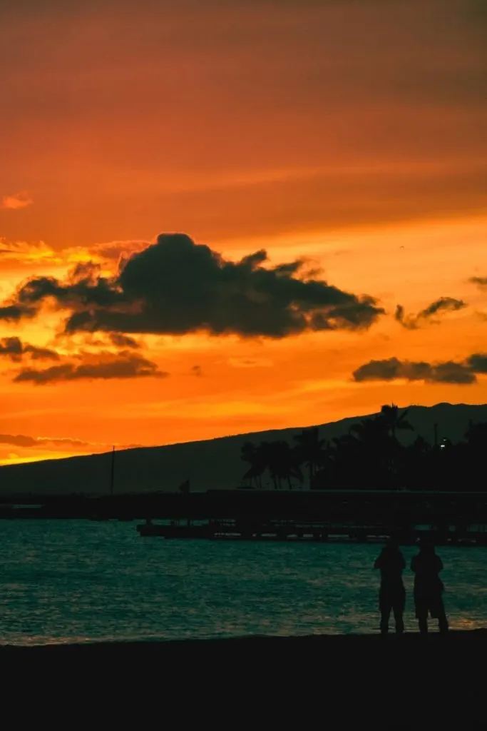 Photo of 2 people watching the sunset from Fort DeRussy Beach on Oahu.