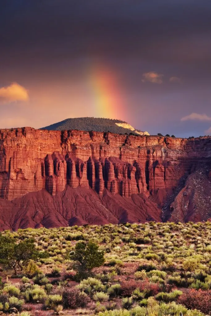 Photo of Red Rock Canyon with a rainbow in the background.