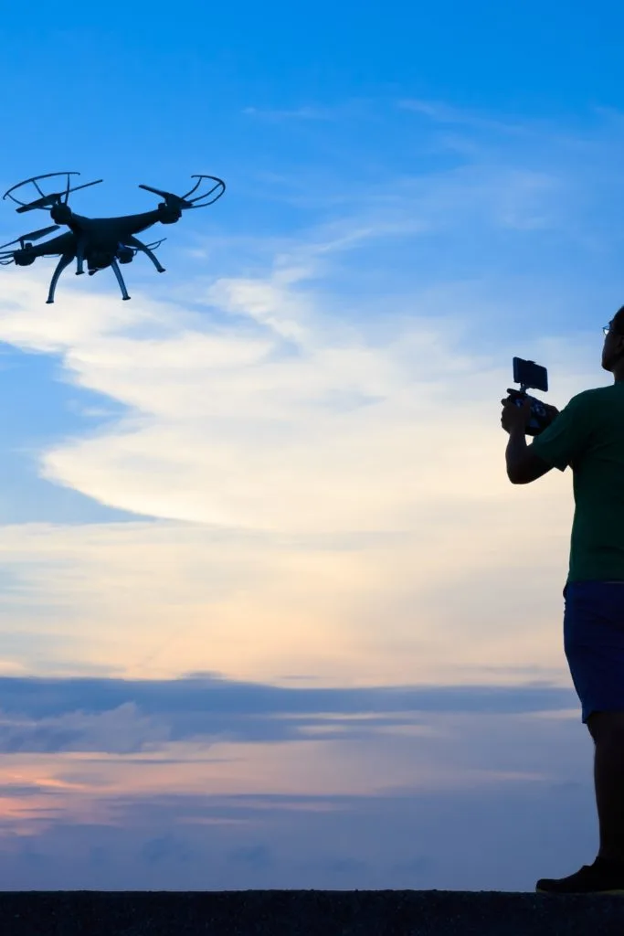 Photo of a person flying a drone against a dusky sky.