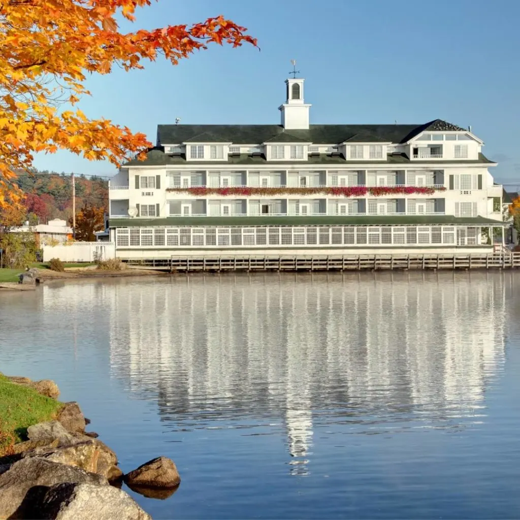 Photo of a lake shore hotel reflecting in the waters of Lake Winnipesaukee in New Hampshire.