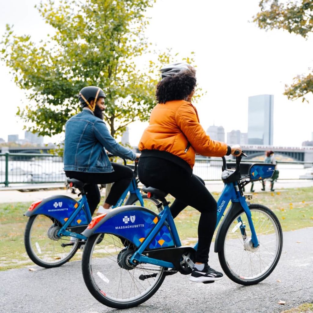 Photo of 2 adults riding blue bikes in Boston.