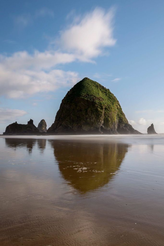 Photo of Haystack Rock reflecting in the wet sand at Cannon Beach, Oregon