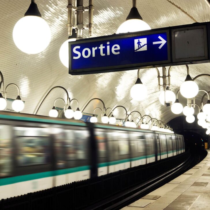 Photo of a sign that says "Sortie" (exit in English) in a Paris train station as a train speeds by.