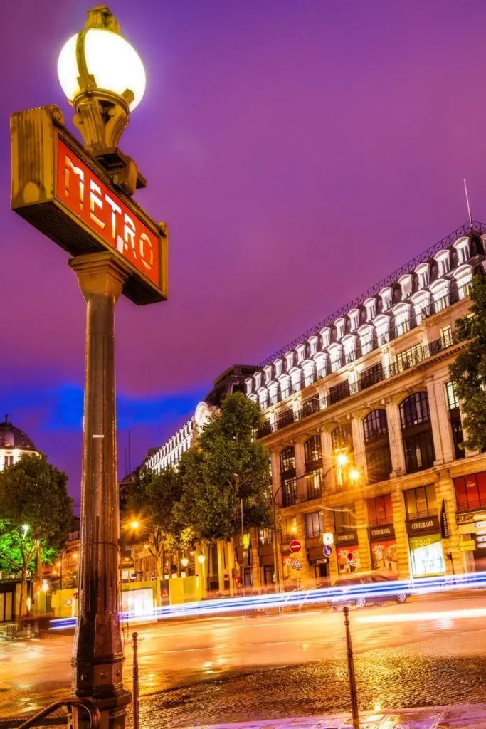 Photo of a red Metro sign in Paris France at night.