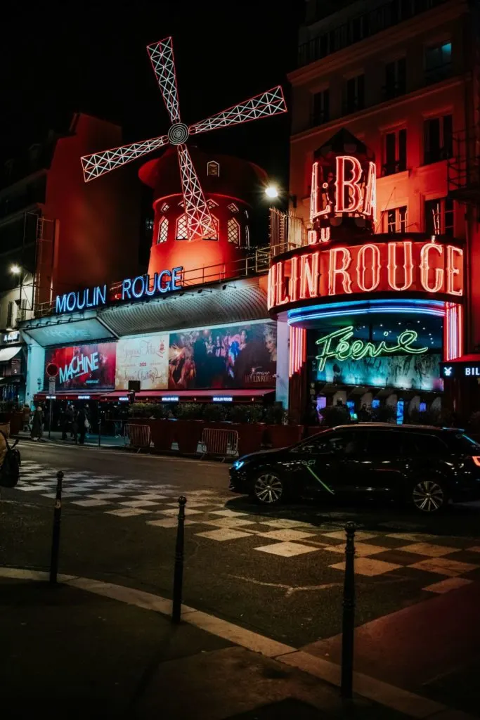 Photo of the exterior of the Moulin Rouge cabaret show in Paris, France at night.