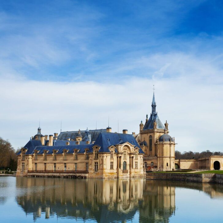 Photo of Château de Chantilly reflecting in the water.