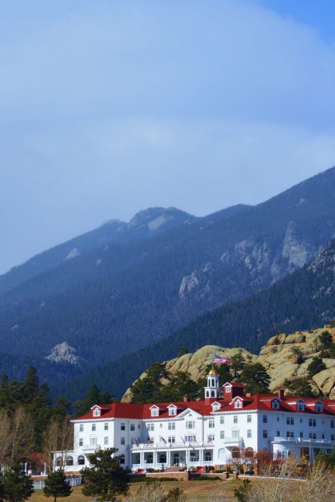 Photo of the exterior of the Stanley Hotel in Estes Park, Colorado, with mountains in the background.