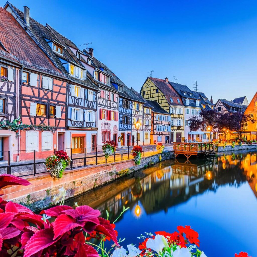 Photo of the town of Colmar, France with colorful buildings reflecting in a canal.