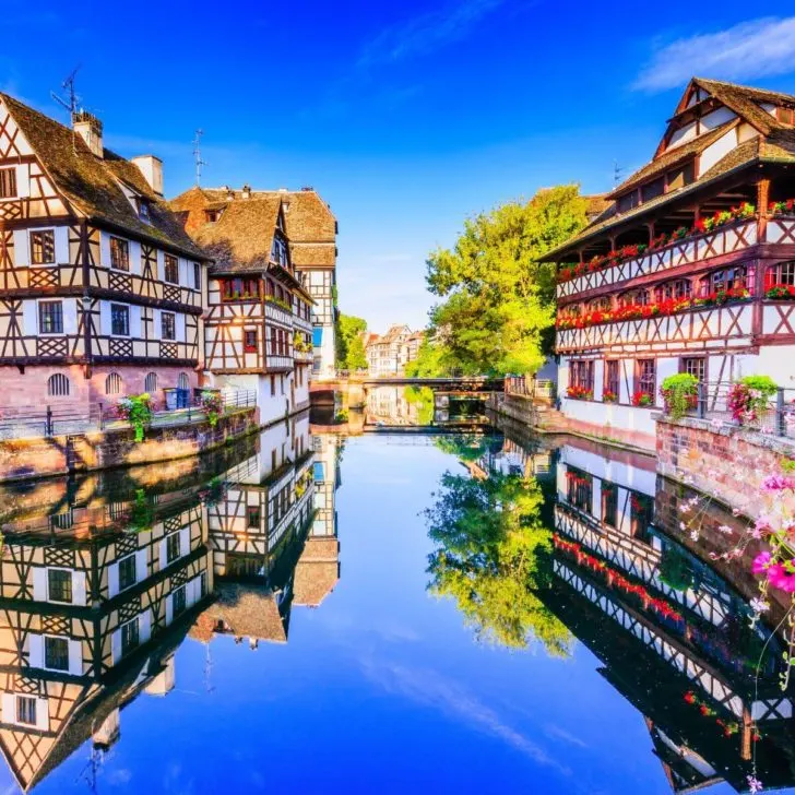 Photo of the German inspired village of Strasbourg in France with colorful, half-timbered houses lining a canal.