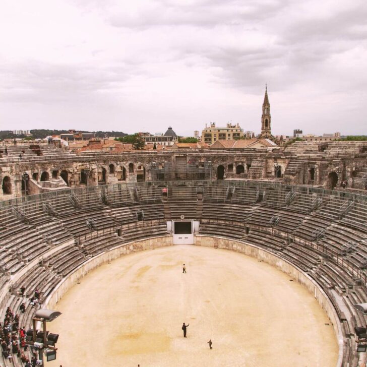 Aerial photo of the Arena of Nimes in France with a small group of people watching a demonstration.