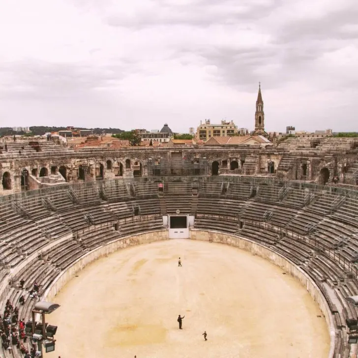 Aerial photo of the Arena of Nimes in France with a small group of people watching a demonstration.