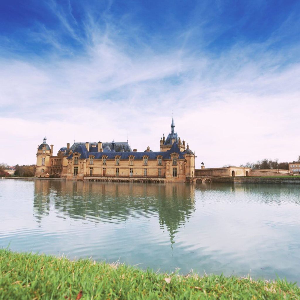Photo of Chateau de Chantilly from across the water surrounding it.