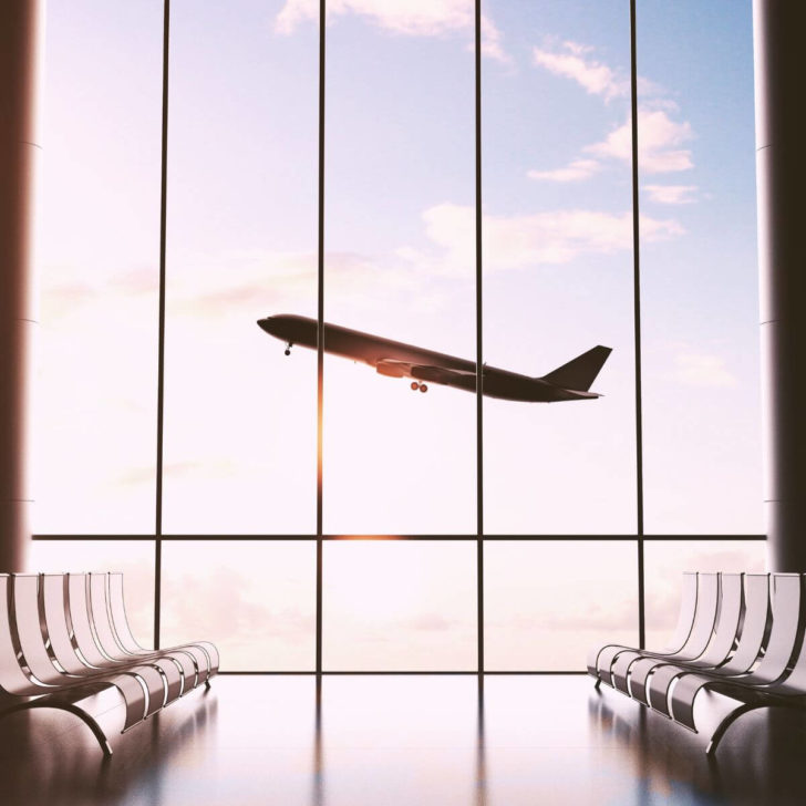 Photo from inside an airport with a plane taking off outside the window.