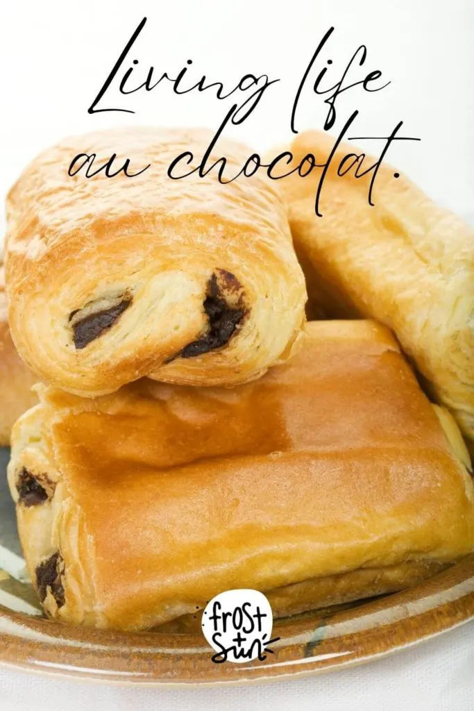 Closeup of a plate stacked with pain au chocolat. Text above the photo reads "Living life au chocolat."