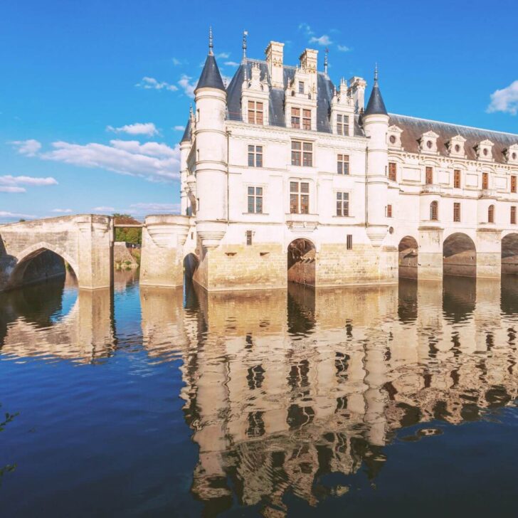 Photo of Chateau de Chenonceau in the Loire Valley of France, reflecting in the water surrounding it.
