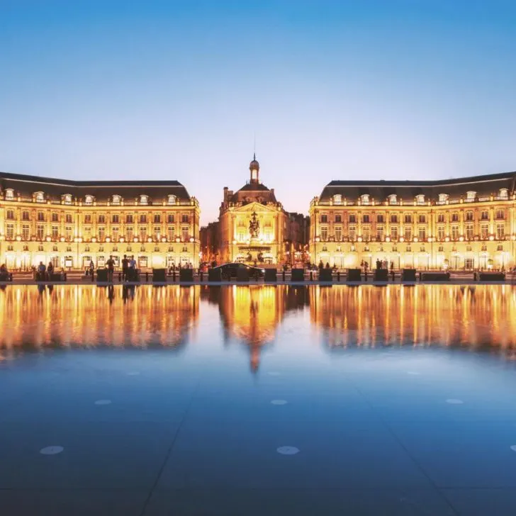 Photo of Place de La Bourse in Bordeaux at night, reflecting in water.