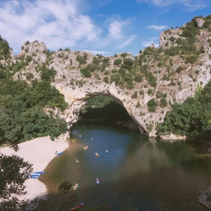 Photo of the Pont d'Arc over the Ardeche River with people kayaking int he waters.