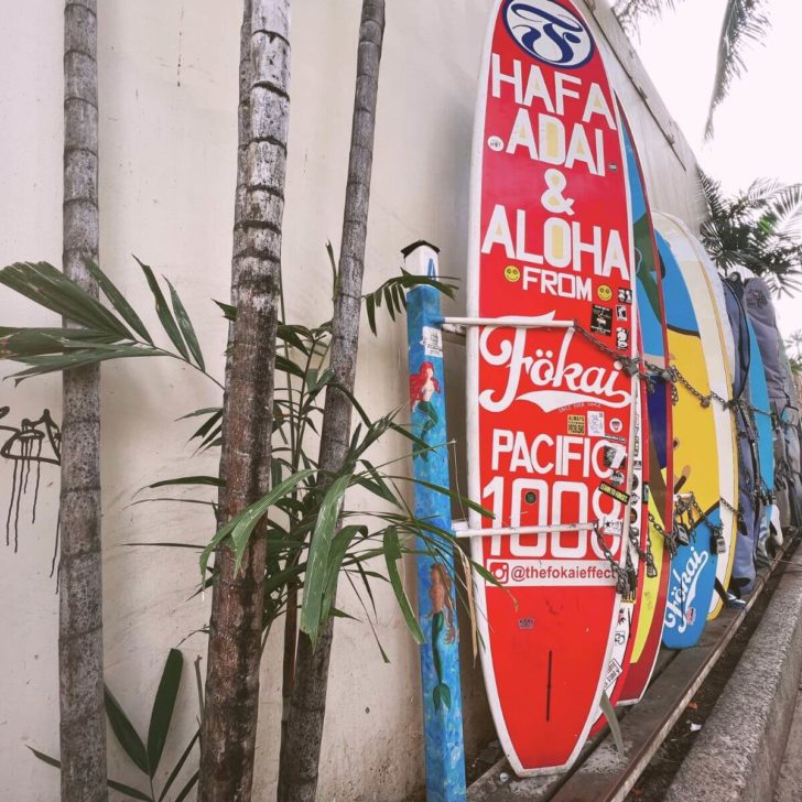 Photo of surfboards lined up along the wall of an alley in Waikiki Beach.