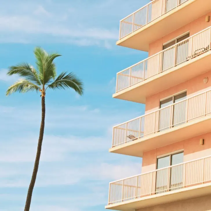 Closeup of a condo vacation rental building in Maui with a palm tree next to the building.