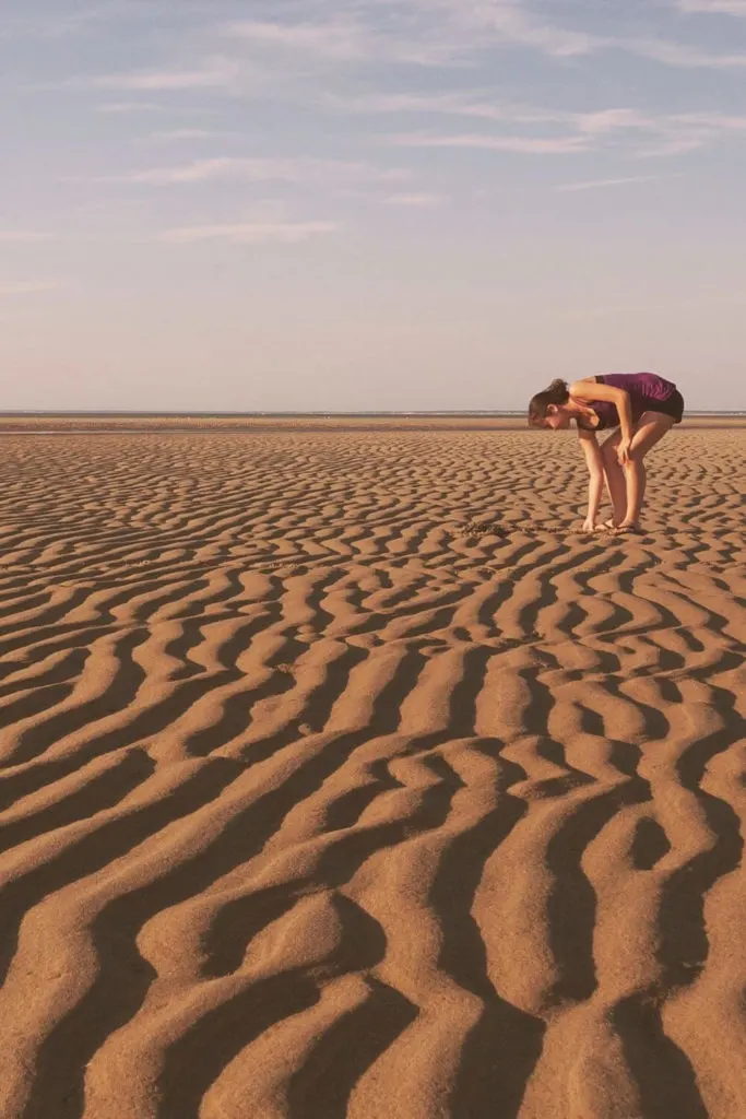 Photo of a woman bending over to pick something up at the Brewster Tidal Flats in Cape Cod, MA.