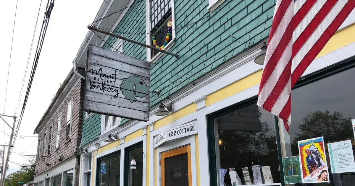 Horizontal photo of the entrance and signage for Mount Dessert Bakery with the American flag next to it.