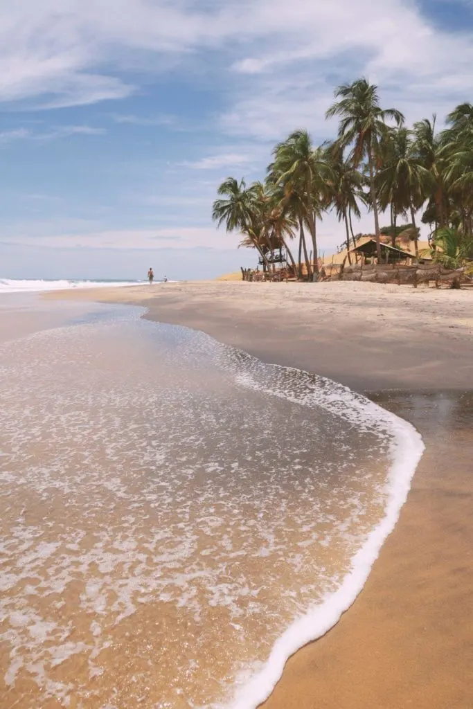 Photo of a beach in Arugam Bay, Sri Lanka, with palm trees in the distance.