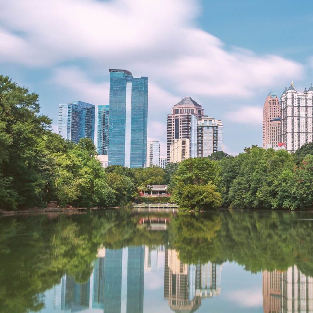 Photo of tall city buildings reflecting in a lake in midtown Atlanta, GA.