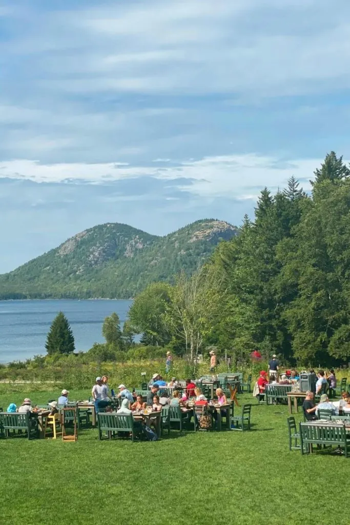 Photo of the lawn behind Jordan Pond House restaurant with Jordan Pond and the Bubbles mountains in the background.