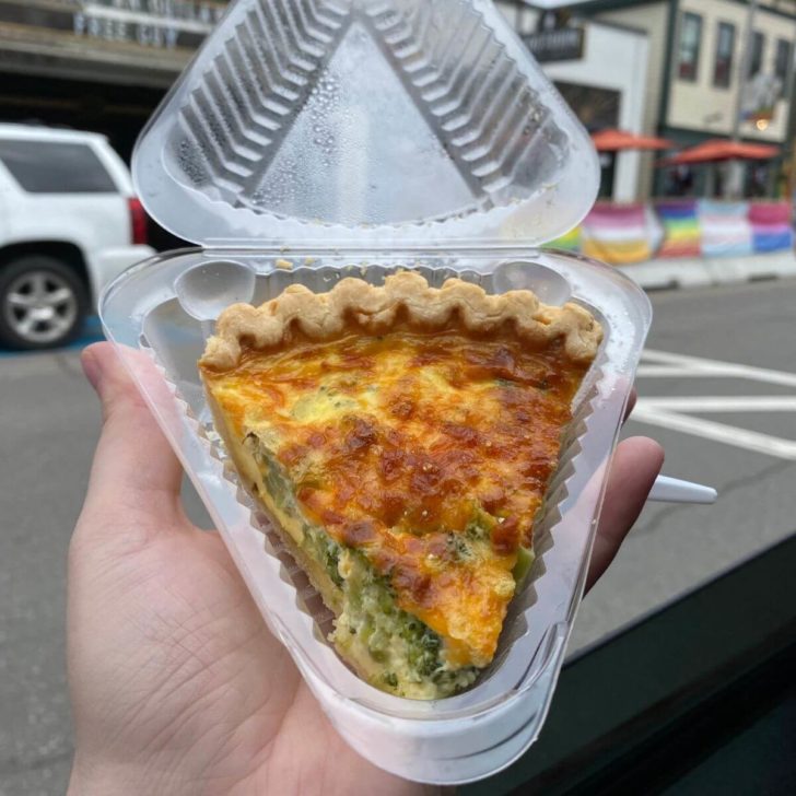 Photo of a fresh broccoli and cheese quiche in a to-go container.