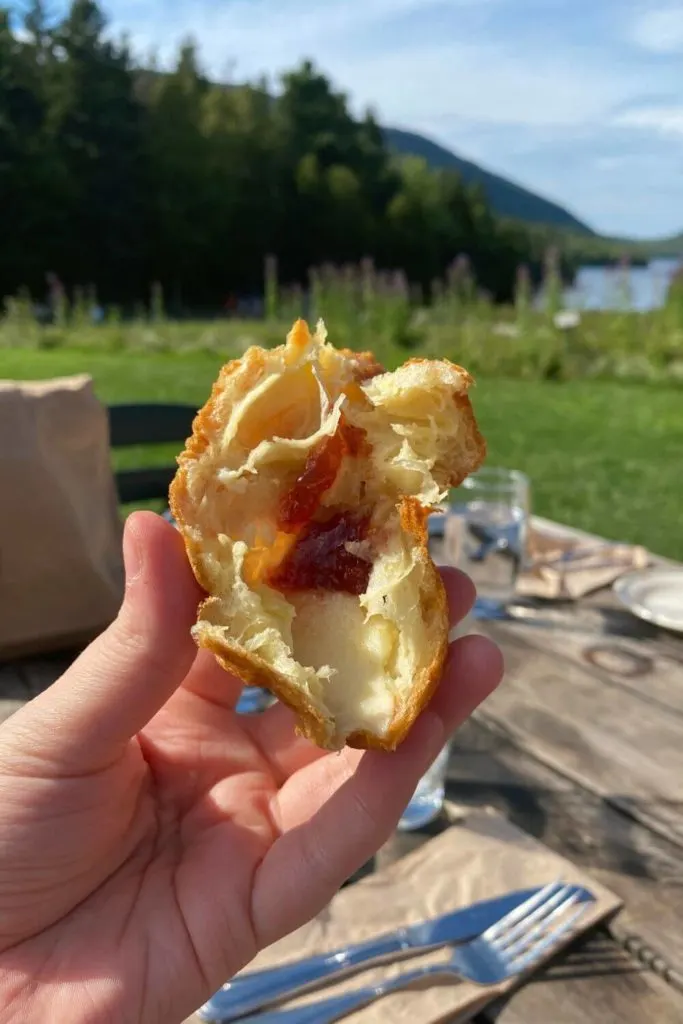 Closeup photo of a popover with fresh strawberry jam with Jordan Pond in the background.