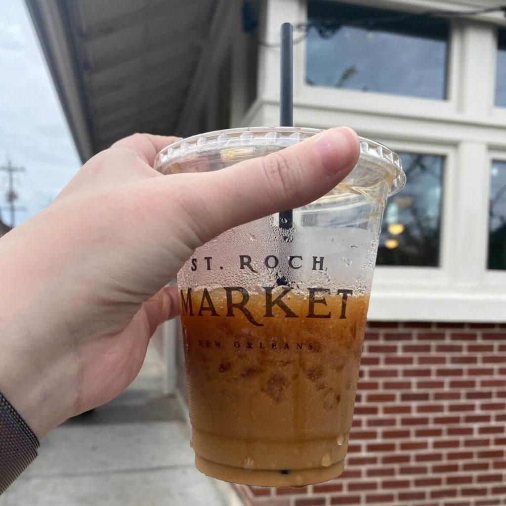Photo of a person holding a cup of iced coffee from St. Roch Market in New Orleans, LA.