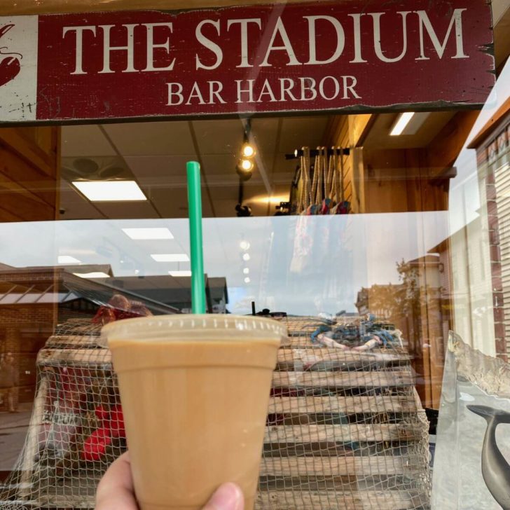 Photo of a cold brew iced coffee in front of a window display at The Stadium Bar Harbor.